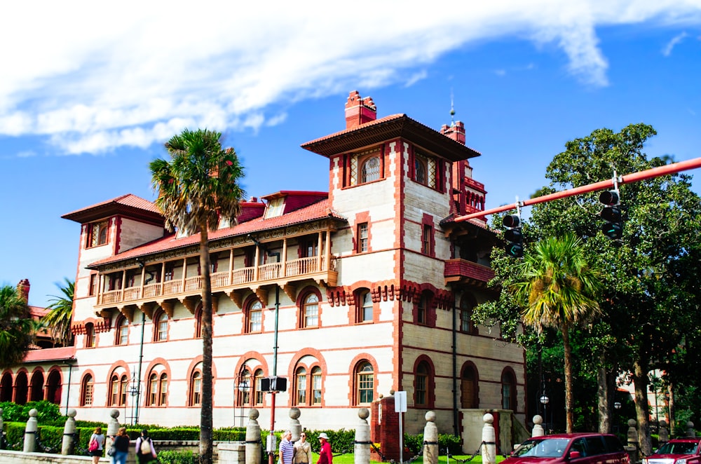 a red car is parked in front of a large building