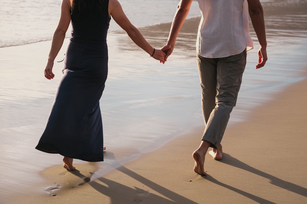 a man and a woman walking on a beach holding hands