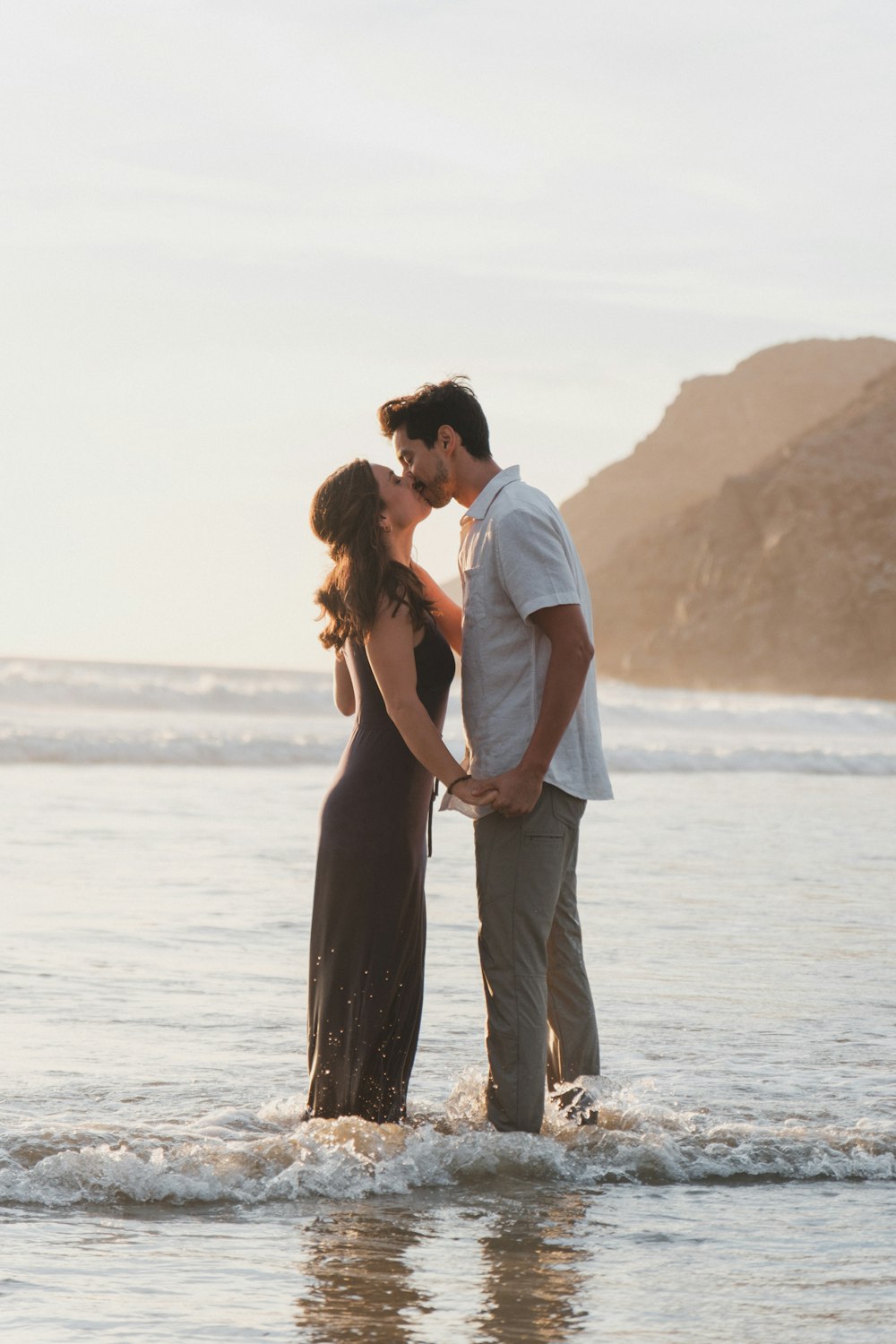 a man and a woman kissing in the ocean