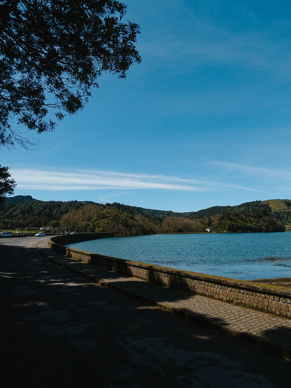 a large body of water sitting next to a lush green hillside