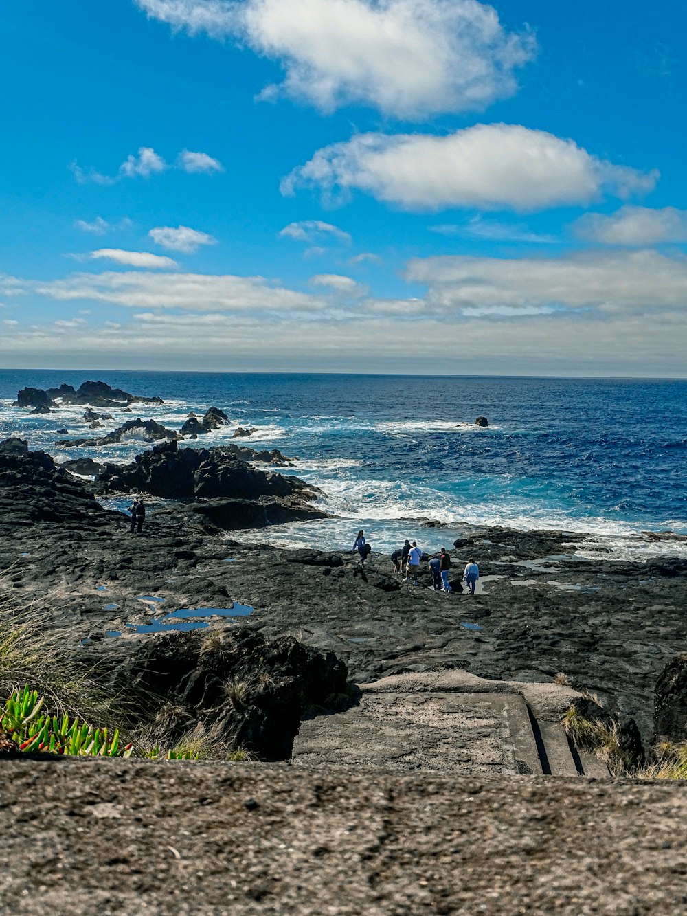 a group of people standing on top of a rocky beach