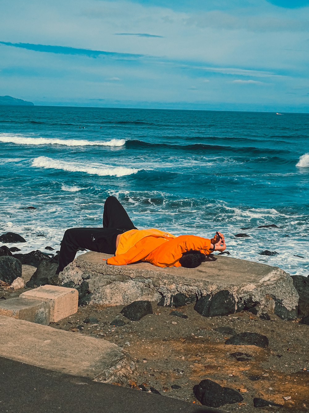 a person laying on a rock near the ocean