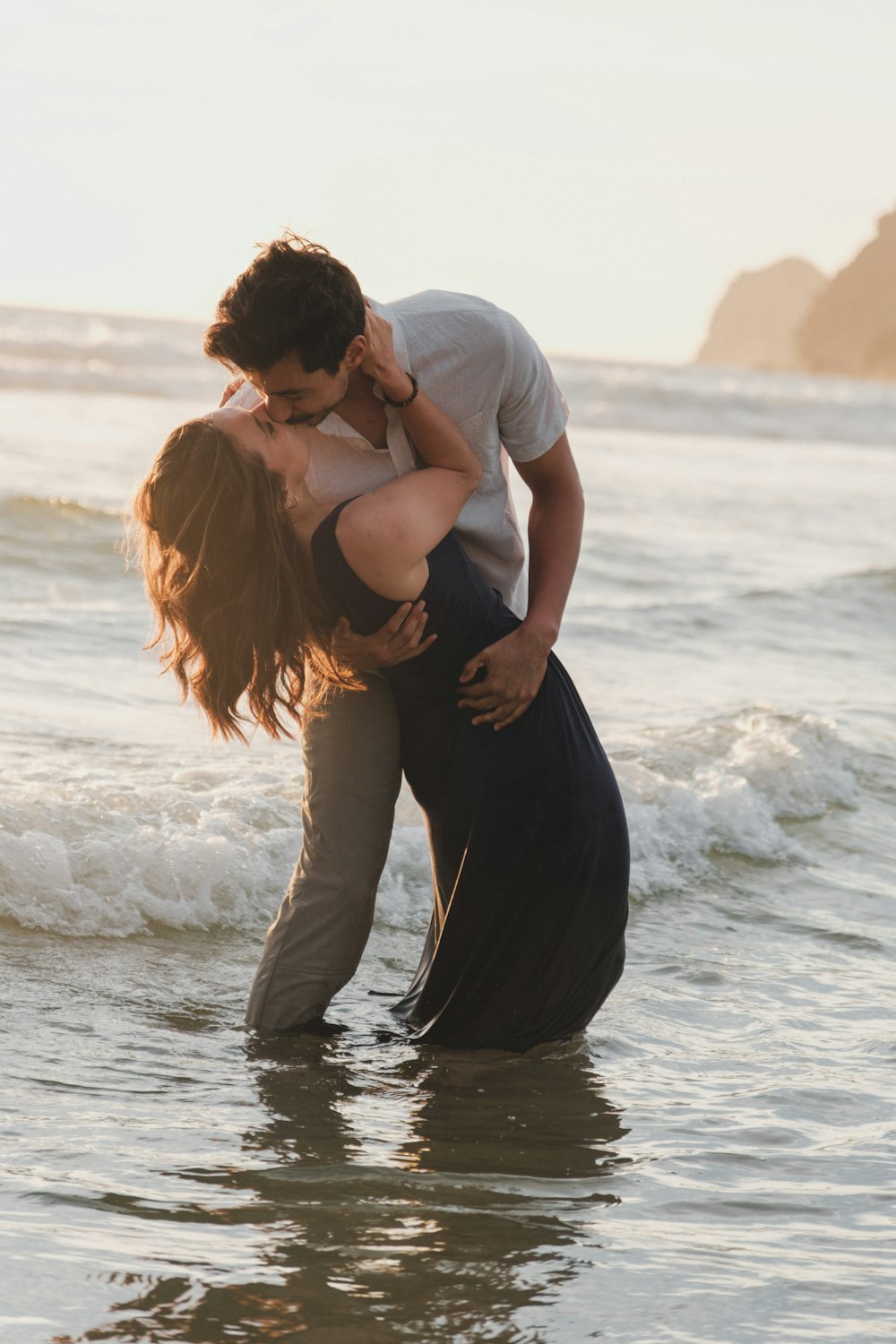 a man and a woman kissing in the ocean