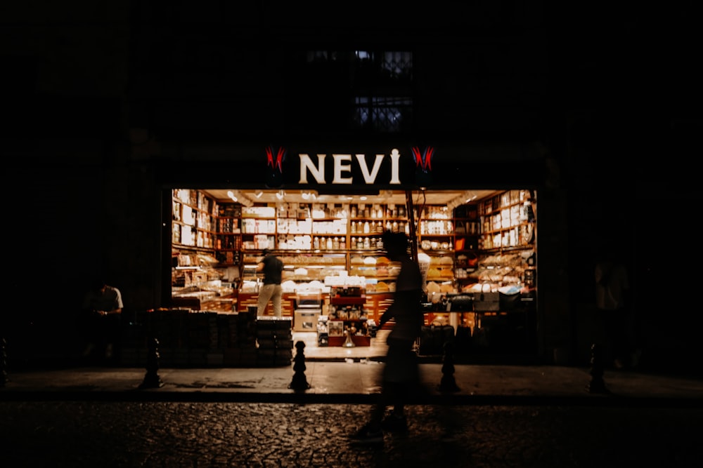 people walking in front of a store lit up at night