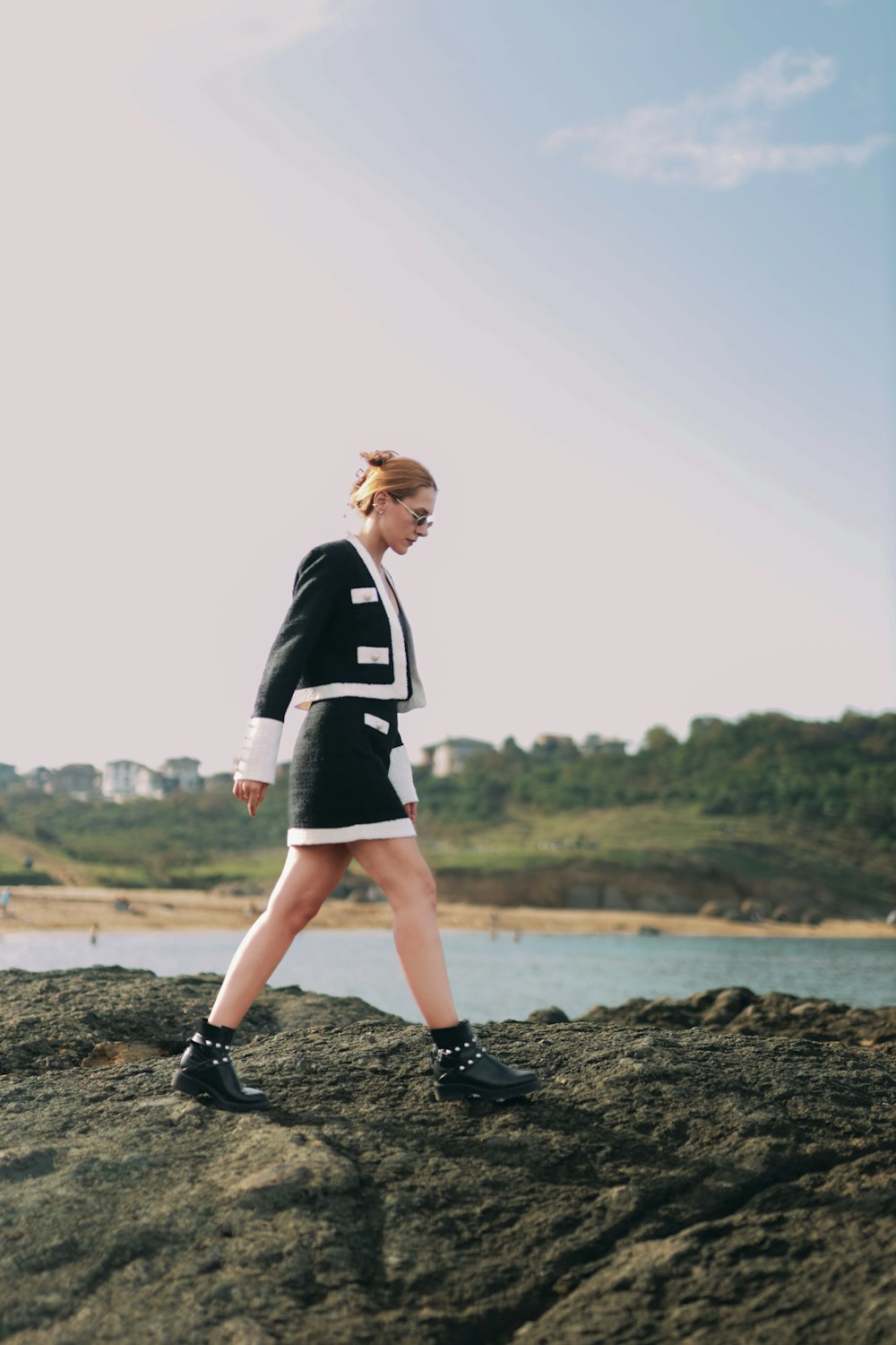 a woman walking along a rocky beach next to a body of water