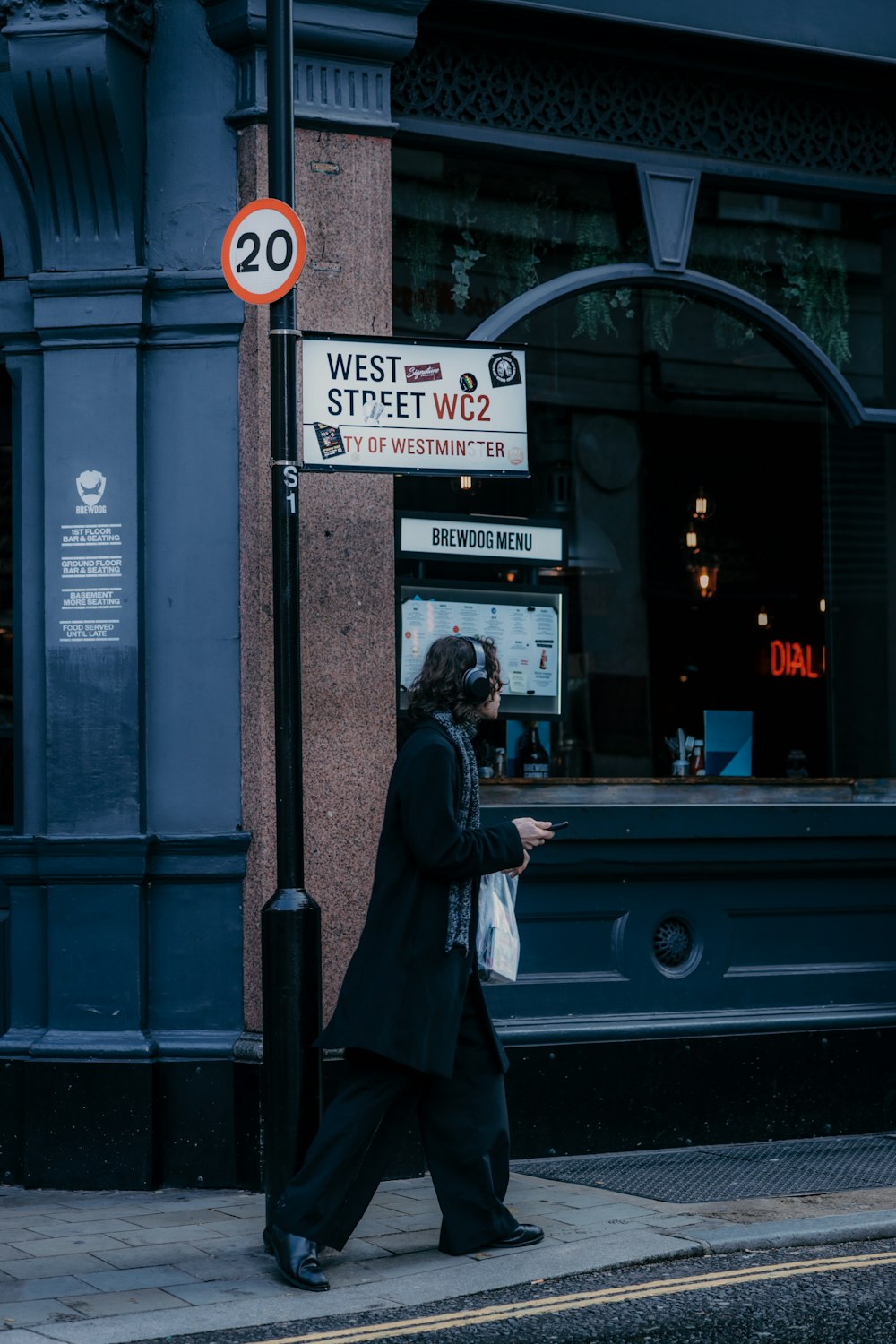 a man walking down a street next to a street sign