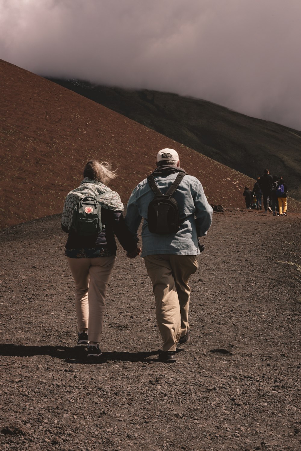 a couple of people walking down a dirt road