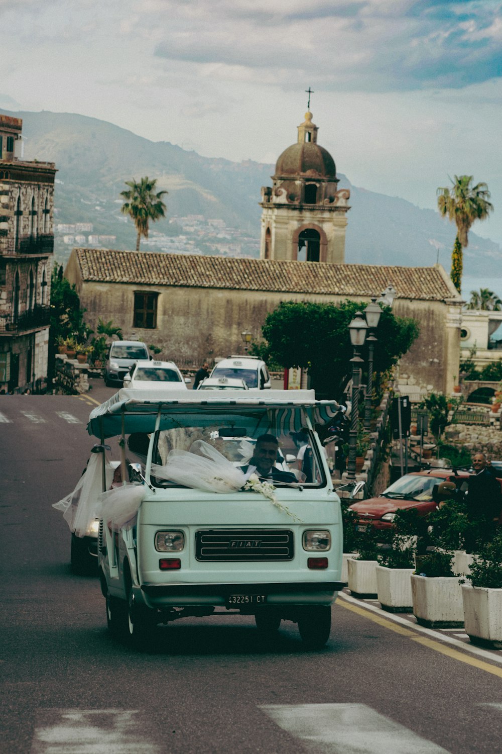 a small car driving down a street next to a tall building