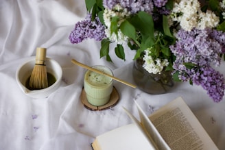 a vase of flowers and a whisk on a table