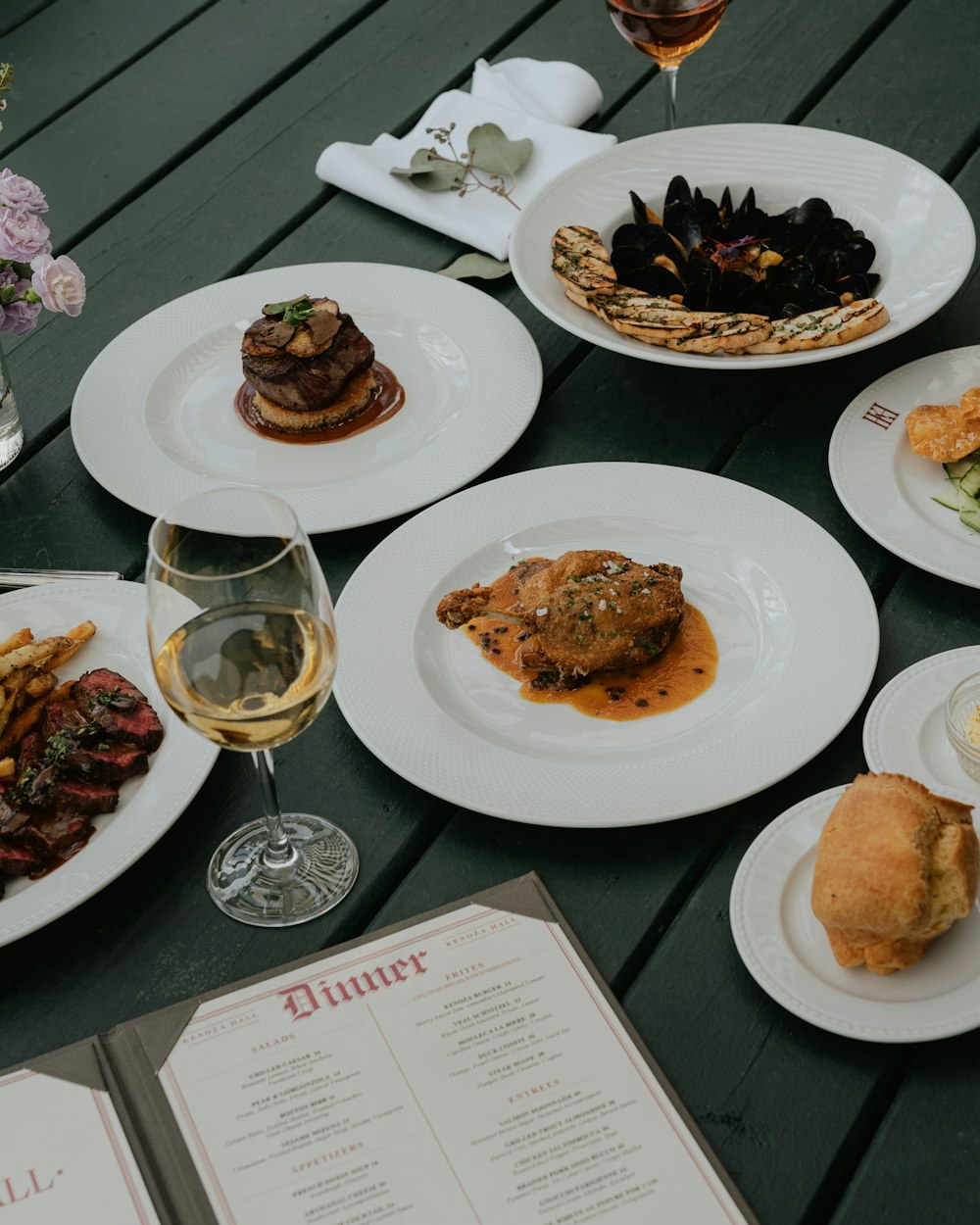 a table topped with plates of food and a glass of wine