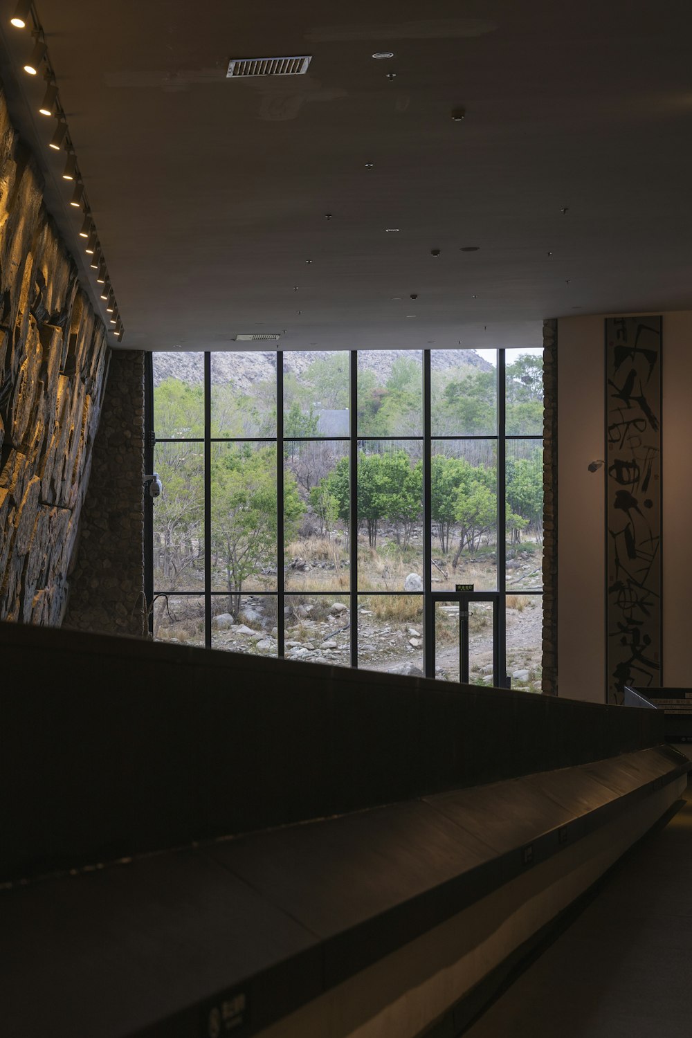 a room with a stone wall and large windows