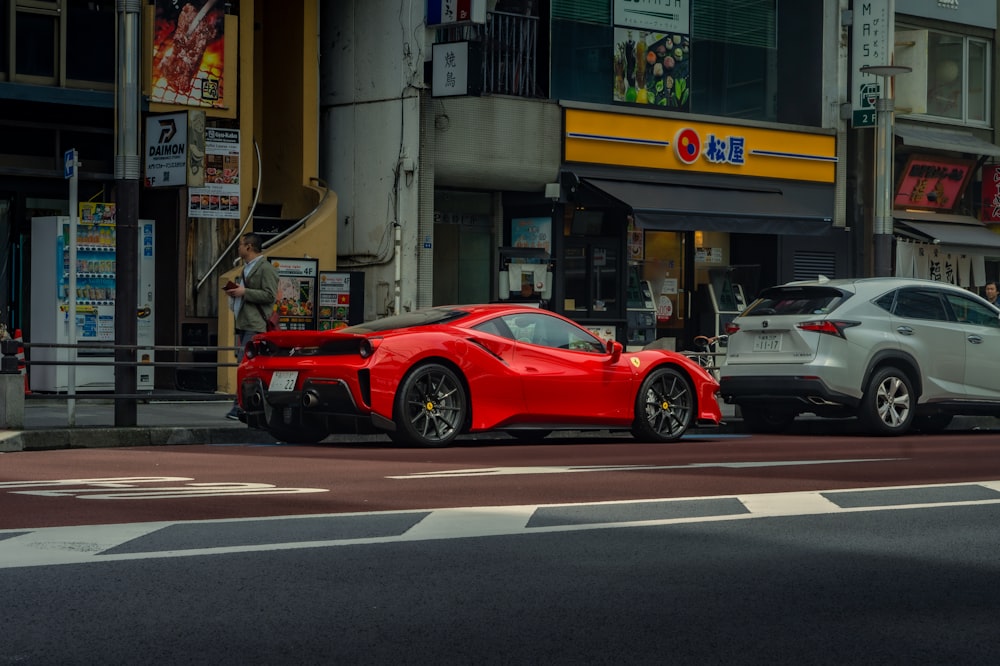 a red sports car parked next to a white car