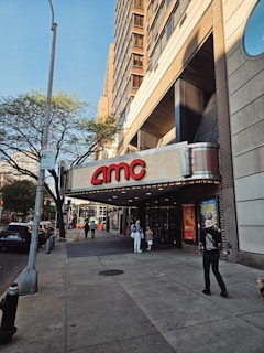 a man standing on a sidewalk in front of a movie theater