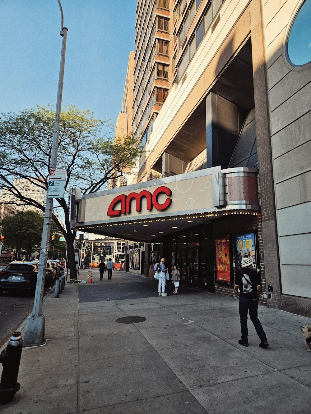 a man standing on a sidewalk in front of a movie theater