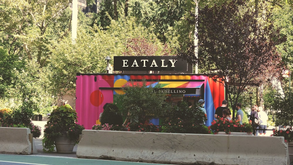 a tennis court with a colorful building and trees in the background