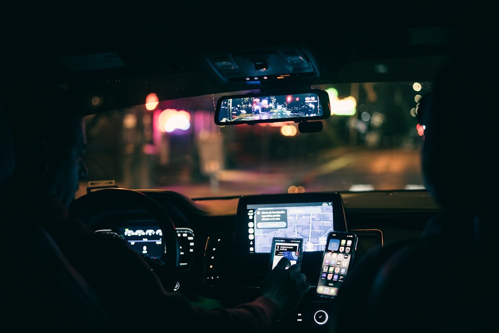 a man driving a car at night using his cell phone