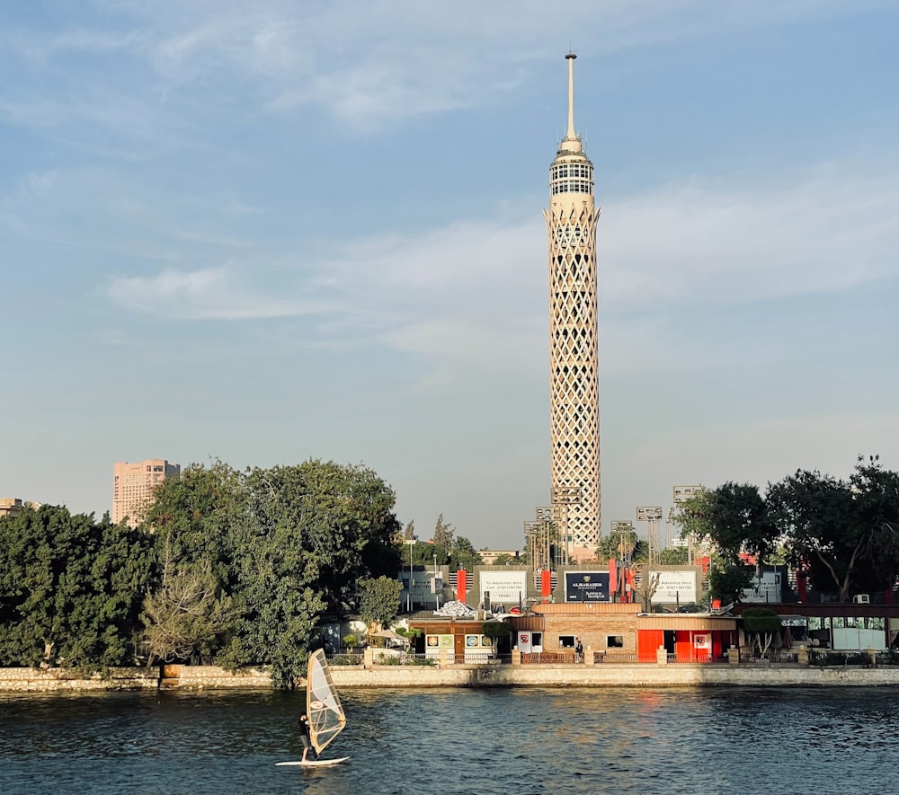 a sailboat in a body of water near a tall tower