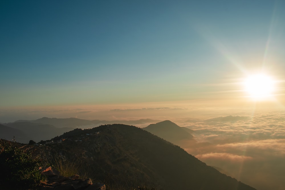 the sun is shining over the mountains above the clouds