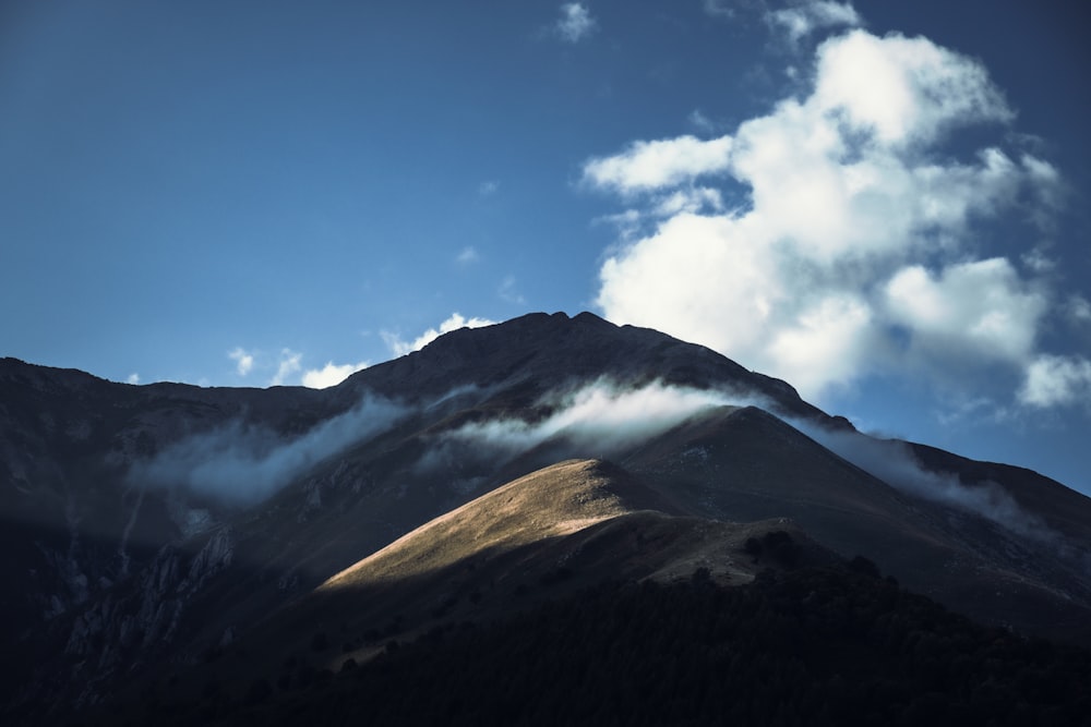 a mountain covered in clouds under a blue sky