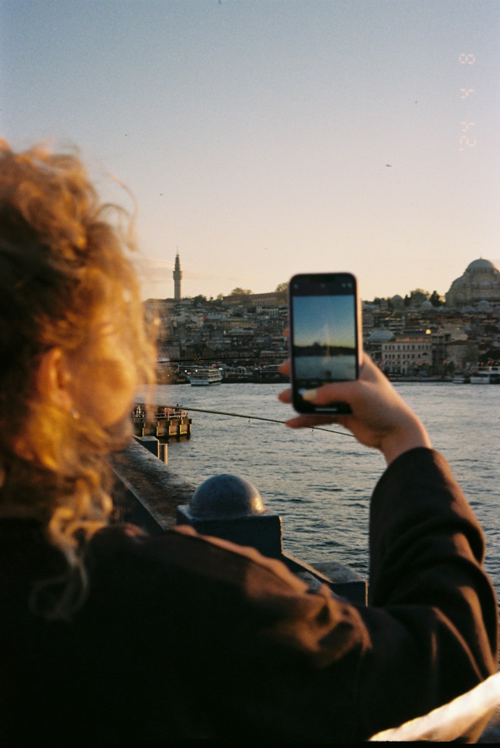 a woman taking a picture of the water with her cell phone