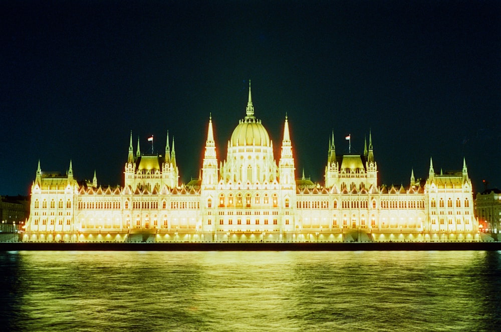 a large building lit up at night with water in front of it