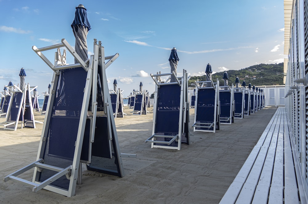 a row of blue chairs sitting on top of a sandy beach