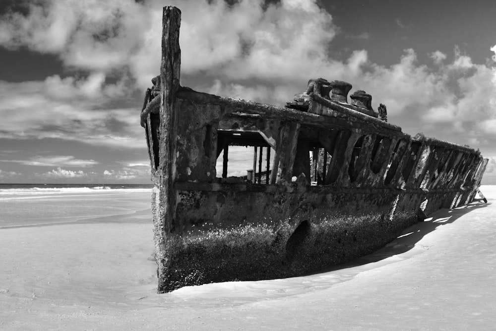 a black and white photo of an old boat on the beach