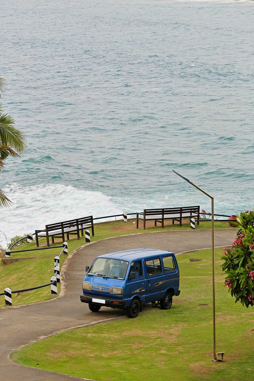 a blue van driving down a road next to the ocean