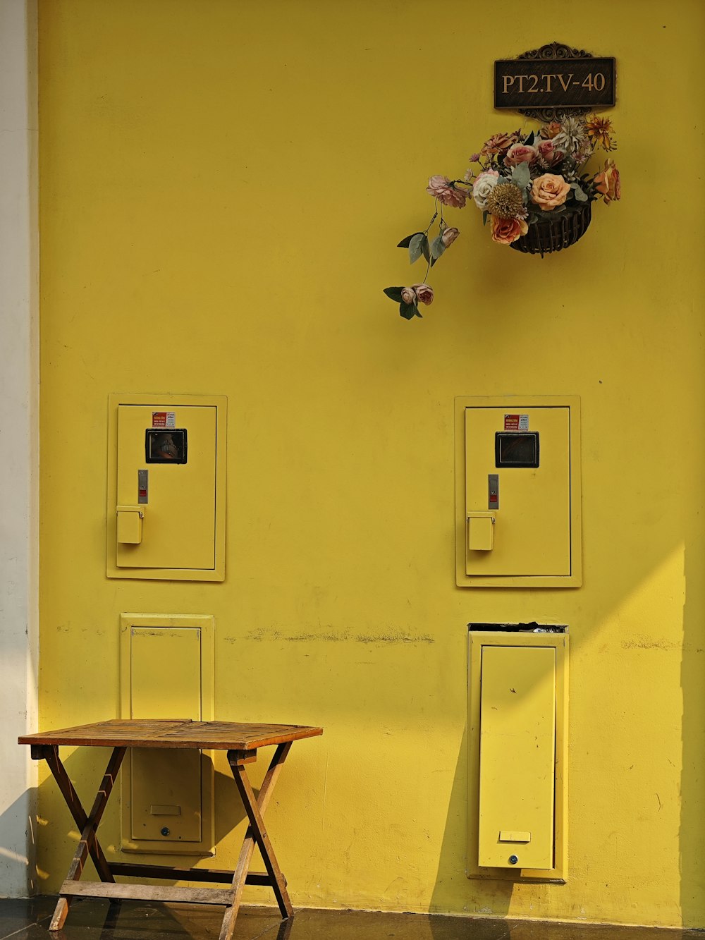 a yellow wall with a table and two switch boxes