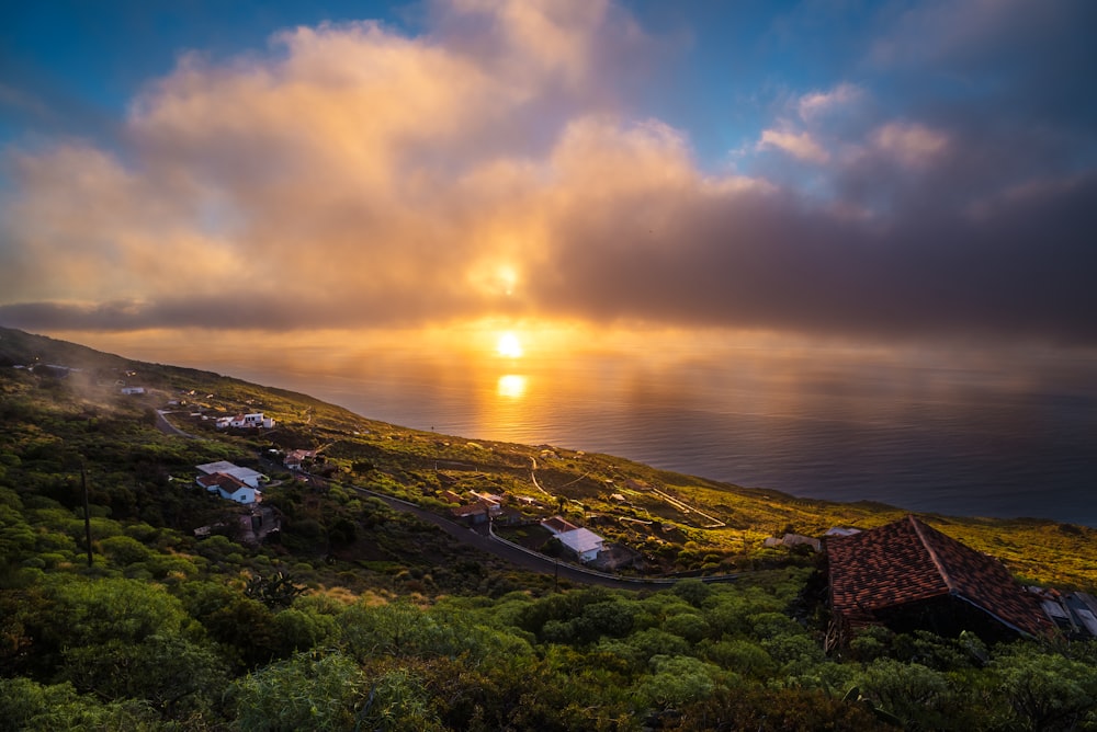 the sun is setting over the ocean on a cloudy day