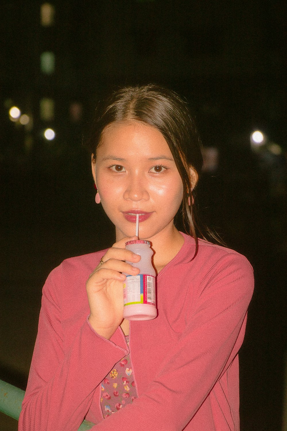 a girl in a pink shirt is holding a drink