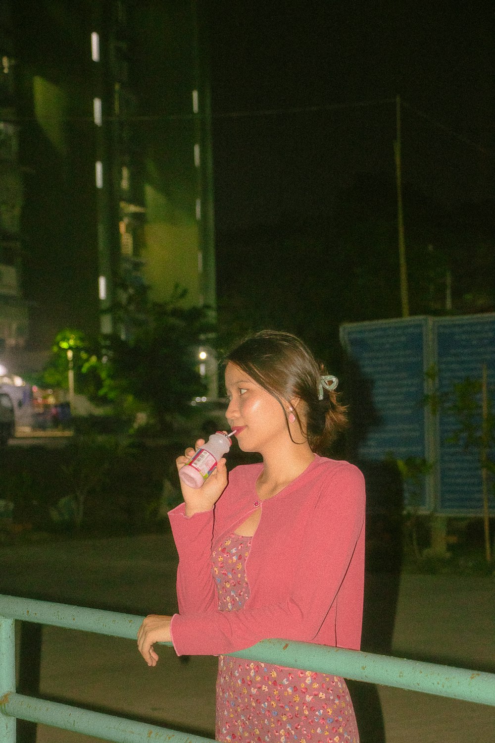 a woman in a pink shirt is drinking from a bottle