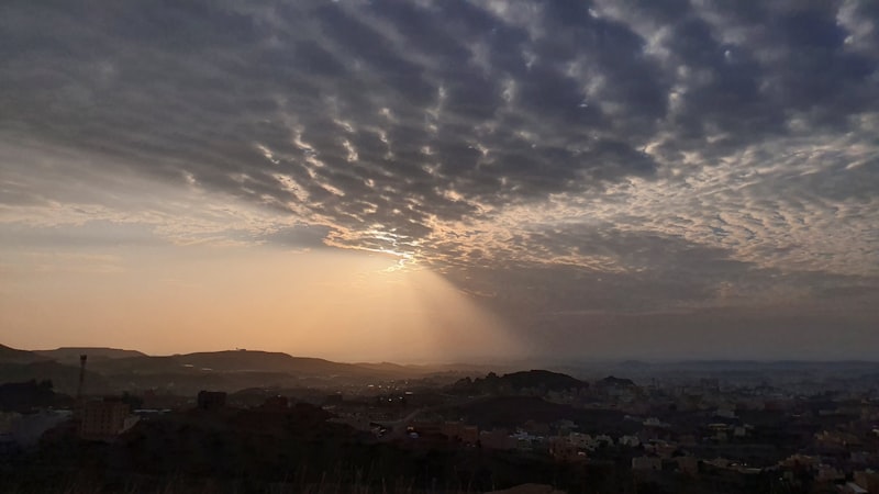 the sun is shining through the clouds over a city