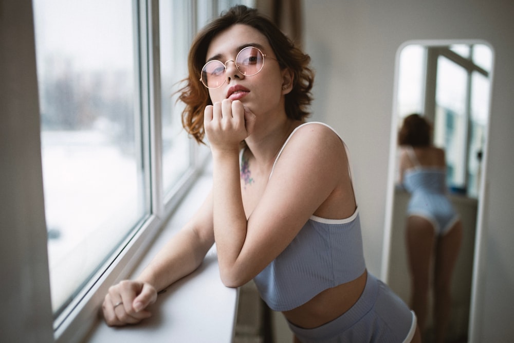 a woman with glasses looking out of a window