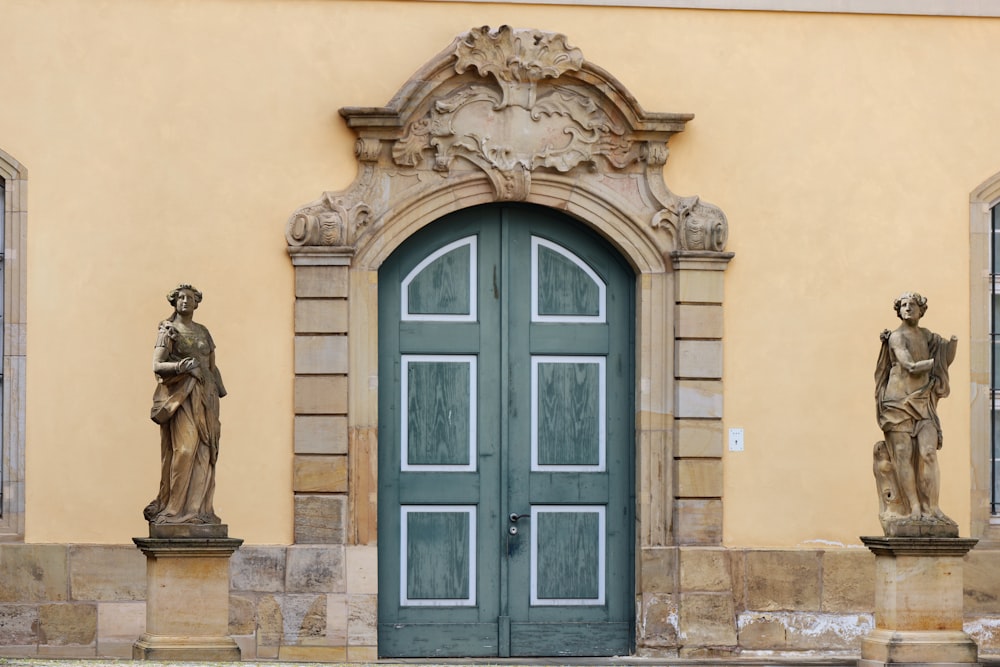 a green door with statues on either side of it