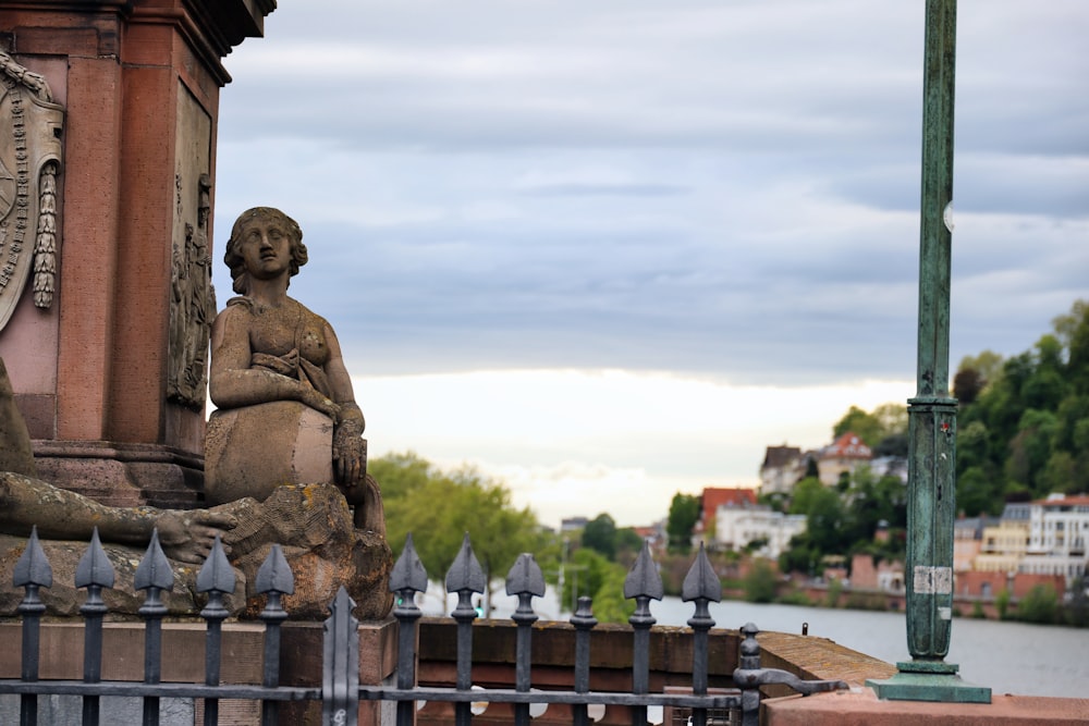 a statue of a woman sitting on a bench next to a fence