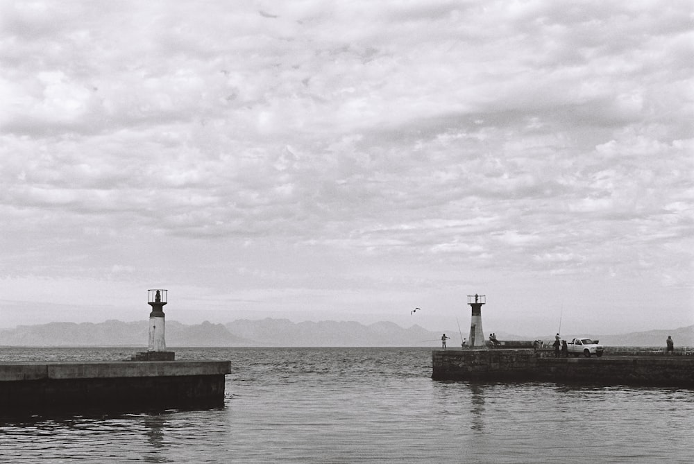 a black and white photo of a lighthouse on a pier