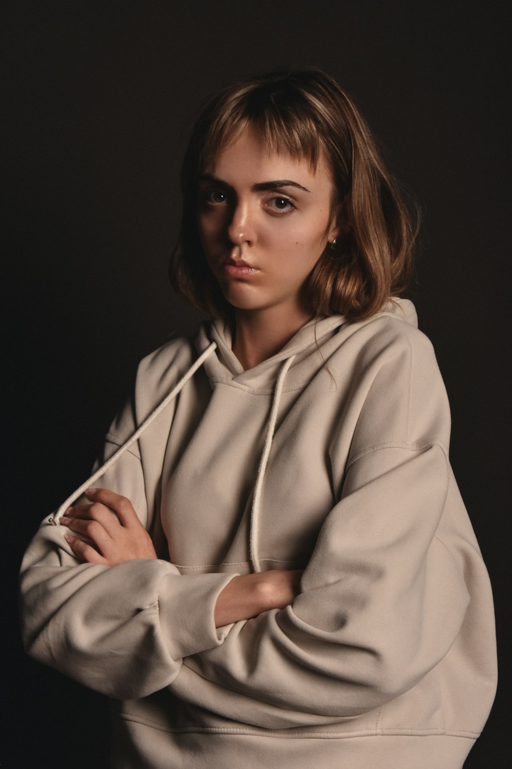 a woman with her arms crossed wearing a hoodie