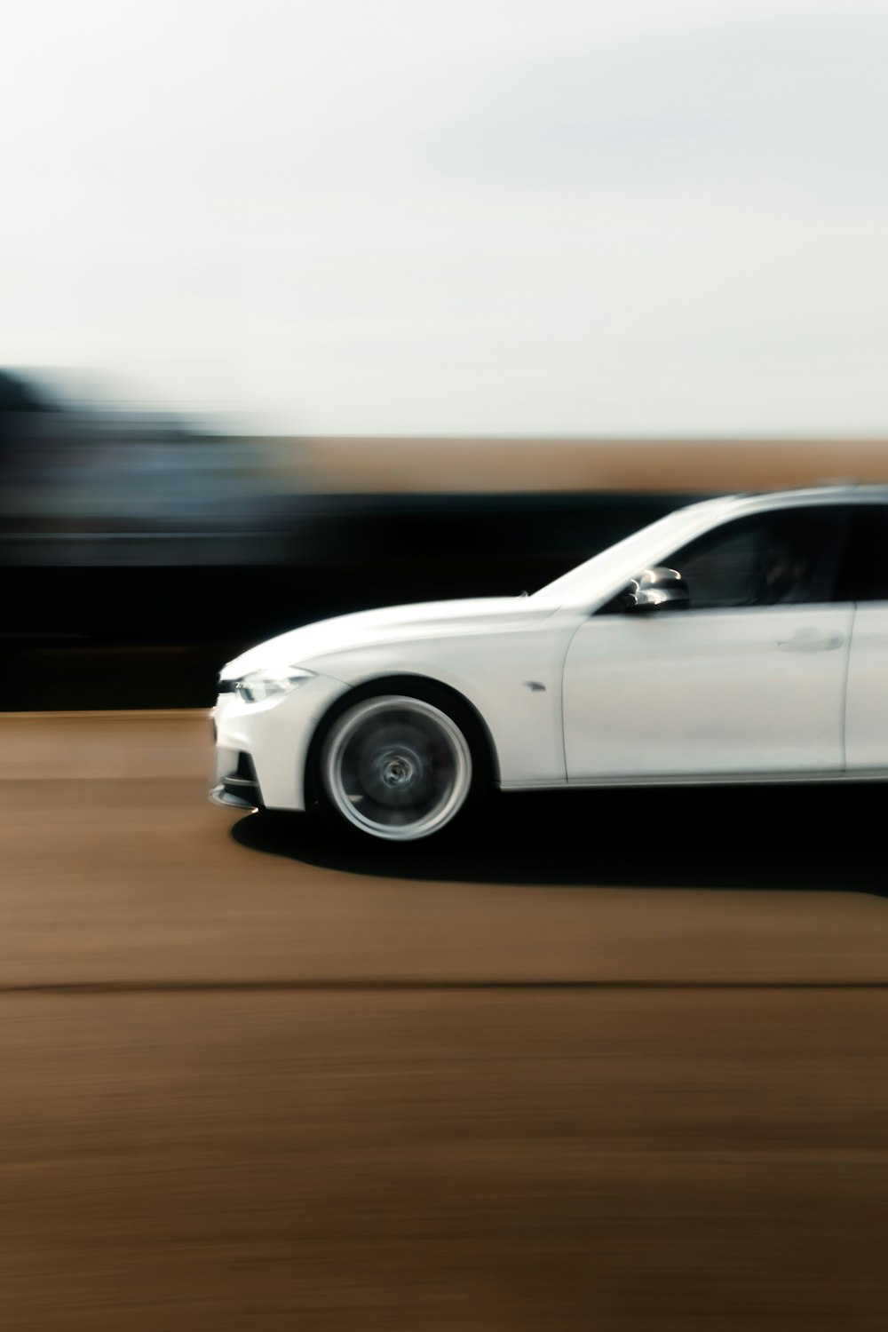 a white car driving down a road next to a forest