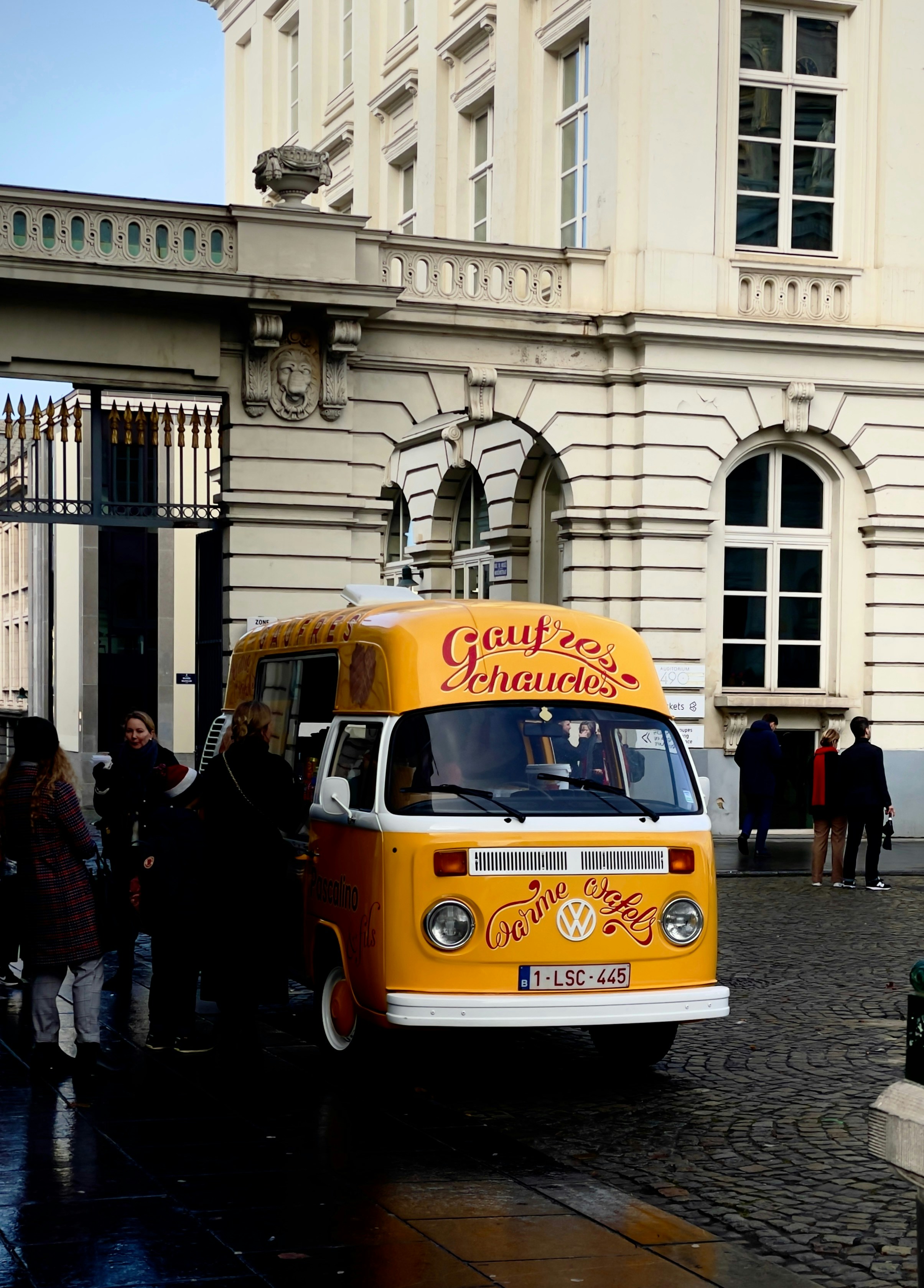 a yellow and white bus parked in front of a building