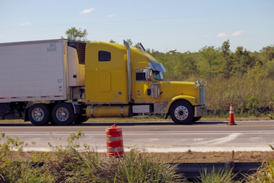 a yellow semi truck driving down a road