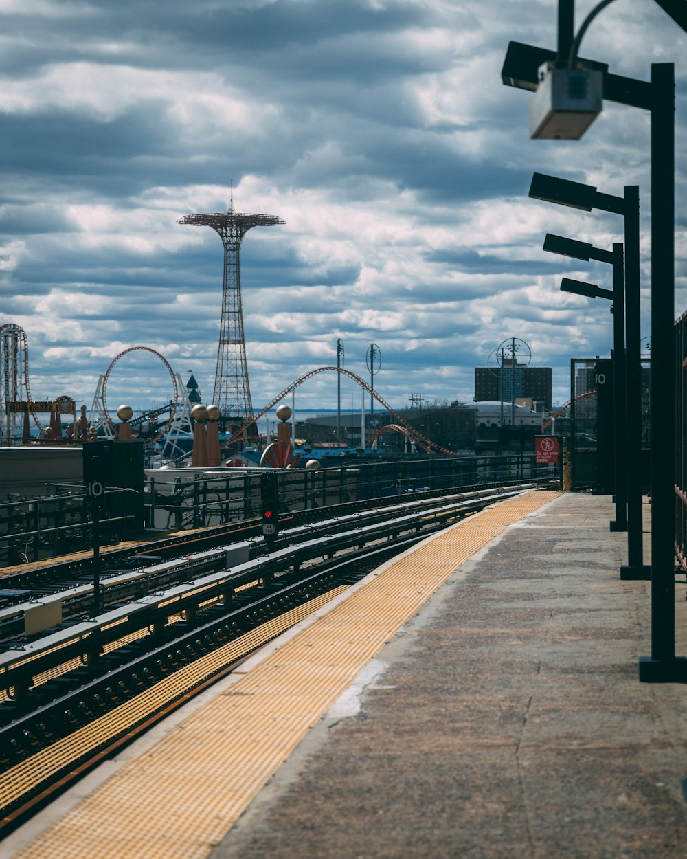 a view of a train station with a roller coaster in the background