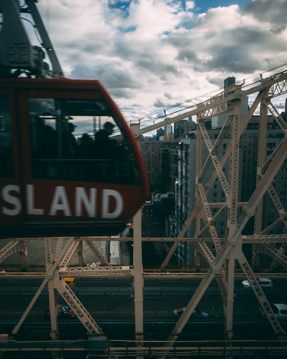 a red train traveling over a bridge next to tall buildings