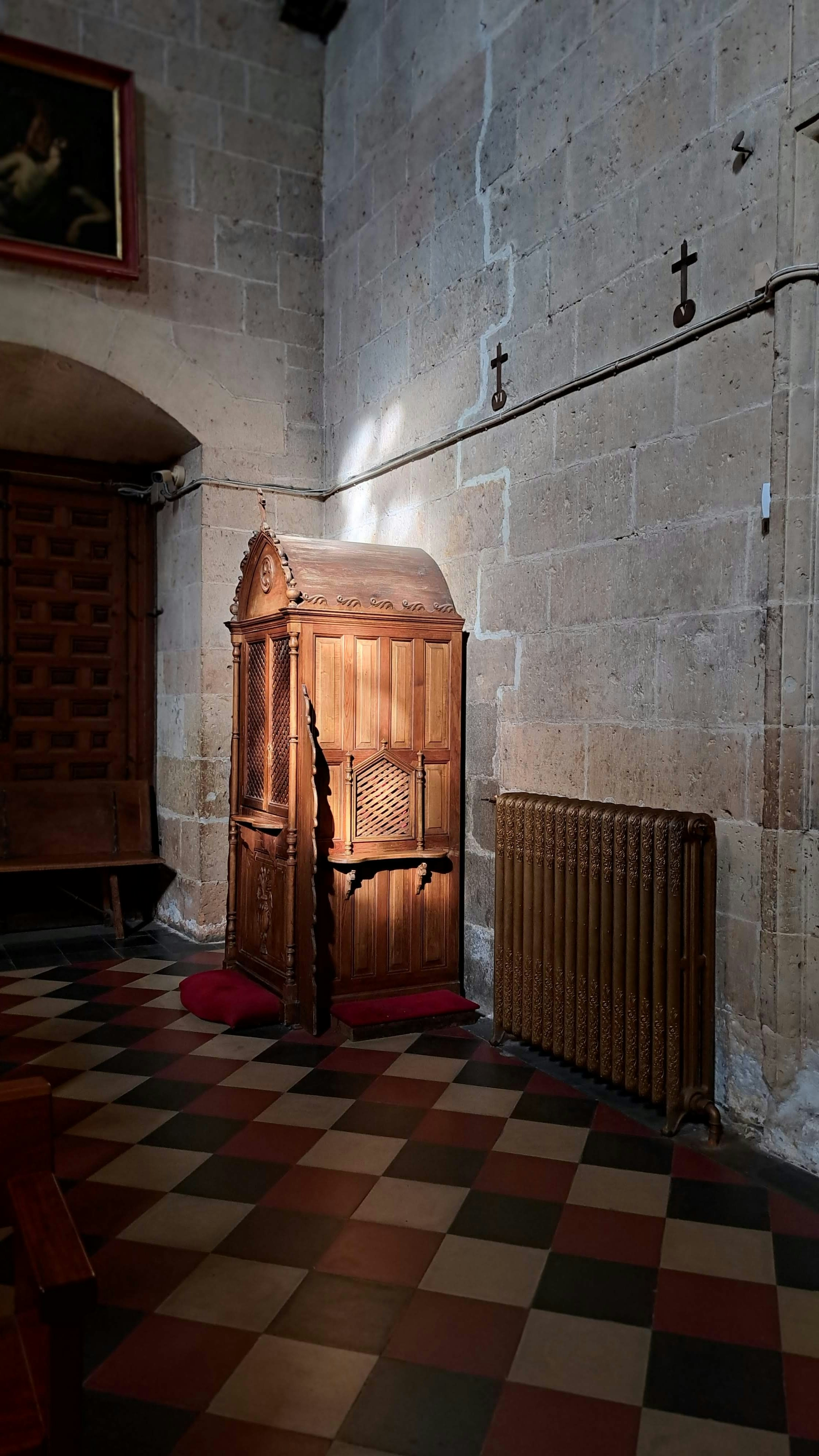 Interior of a Catholic church, confessional booth, warm amber lighting, quiet and reverent