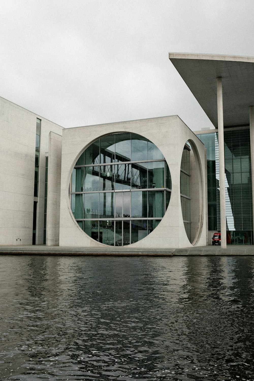 a building with a circular window next to a body of water