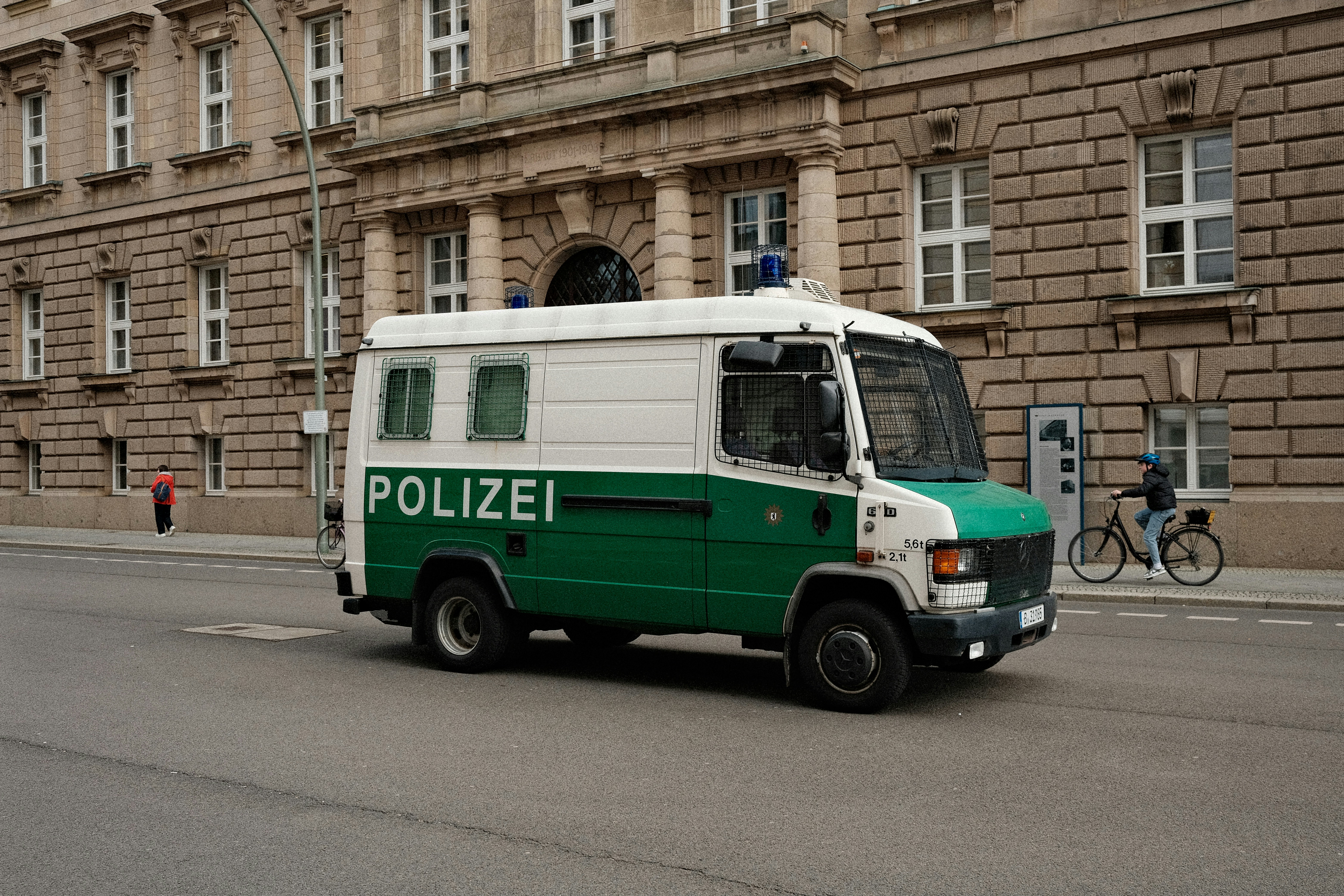 a green and white police van driving down a street