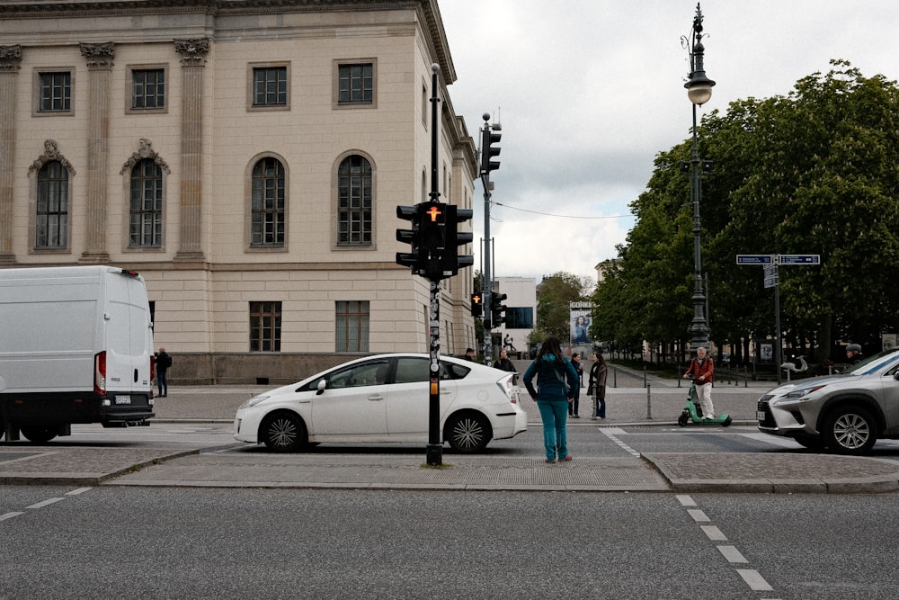 a woman standing next to a white car at a traffic light