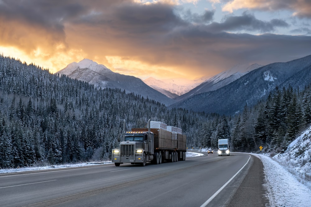 a semi truck driving down a road in the mountains