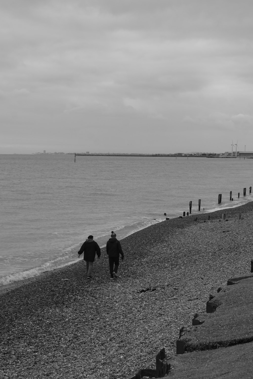 a couple of people walking down a beach next to the ocean