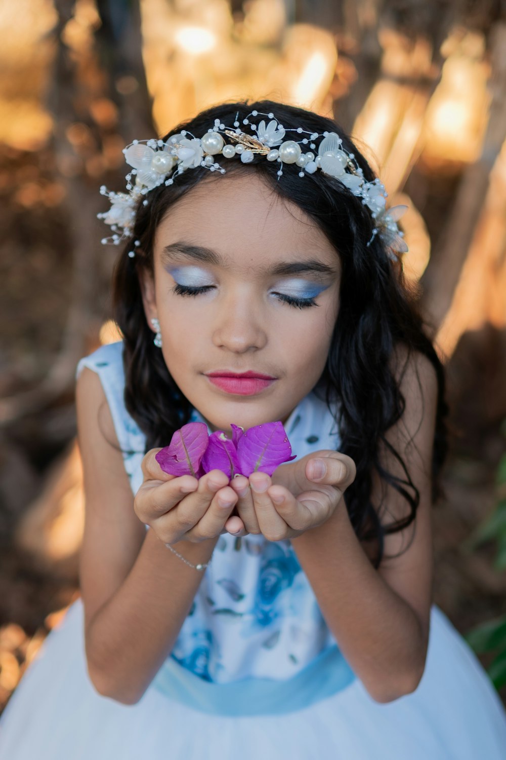 a little girl in a white dress holding a purple flower